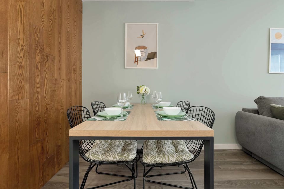 A dining table set for a meal, positioned near a wooden door and decorated with simple tableware.