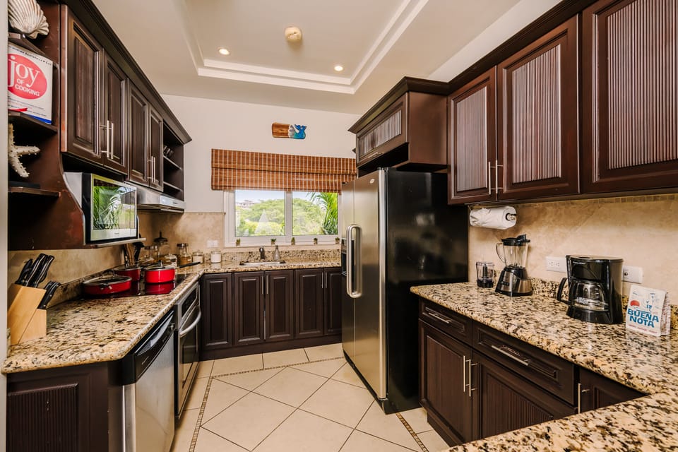 Kitchen at dusk with recessed tray-ceiling cove lighting, dark cabinetry silhouetted, and warm accent light over the arched sculpture niche.