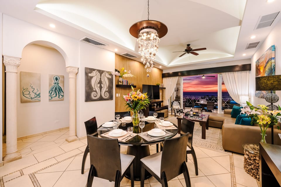 Formal dining with crystal chandelier, table for six, octopus and seahorse art, and open sightline to the balcony.