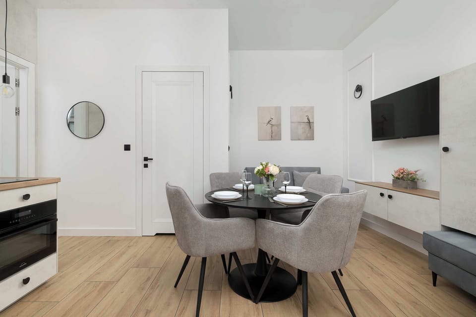 An open space connecting the dining area with the apartment’s entrance, where white walls harmonize with the wooden floor and modern lighting.