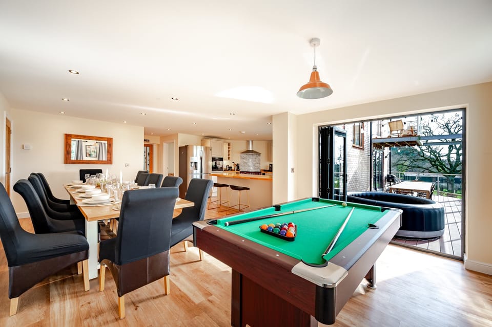 An open-plan haven with a dining table for twelve, sleek kitchen, and pool table—perfect for entertaining, cooking, and relaxing together.