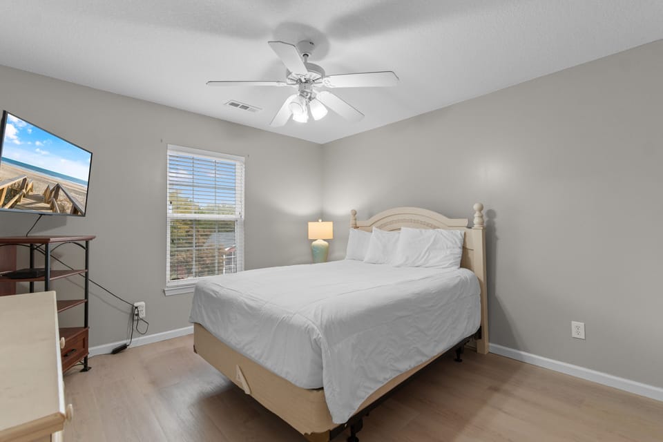 Drift off in this peaceful bedroom with crisp linens, gentle ceiling fan, and calming natural light from your window.