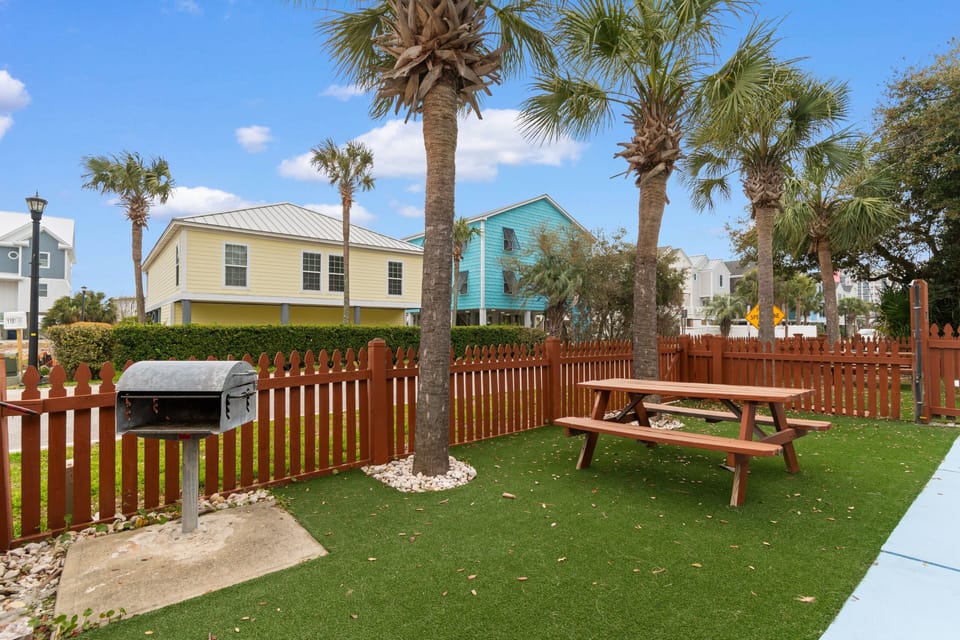 Your private backyard oasis features a grill and picnic table under swaying palms, perfect for outdoor dining and relaxation.