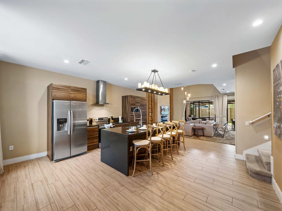 Open-concept kitchen and living area with modern wood cabinetry and a large island for dining.
