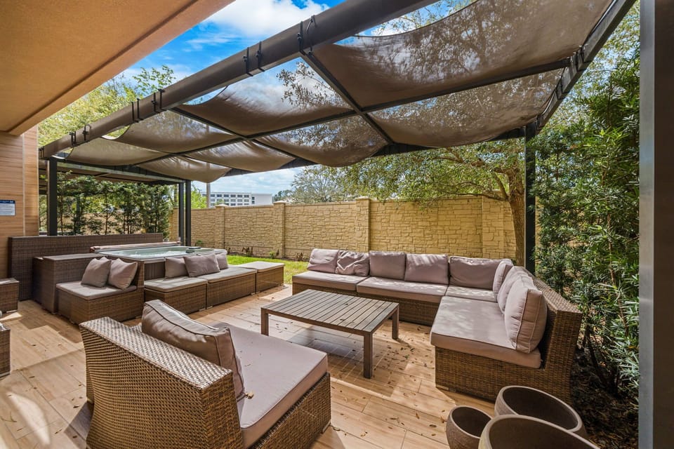 Relax in the shaded outdoor lounge area with cushioned wicker seating and a hot tub.