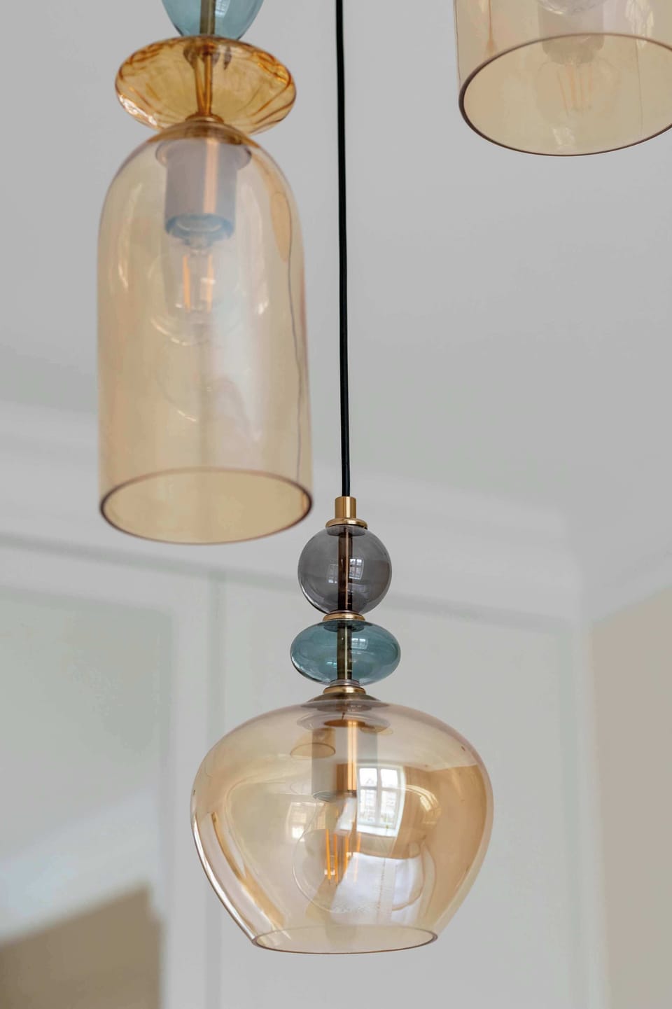 A modern pendant light detail highlights two glass globe fixtures with a warm amber tint. The lights hang at different heights, adding a decorative element to the ceiling.
