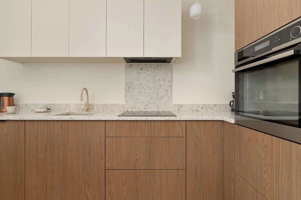 A kitchenette countertop detail shows a built-in oven set into the wood-textured cabinetry. The white upper cabinets provide a bright contrast to the warm tones of the lower units.