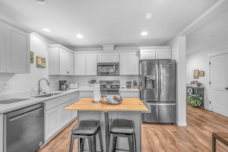Your fully equipped kitchen awaits with modern appliances, butcher block island seating, and everything needed for memorable meals together.