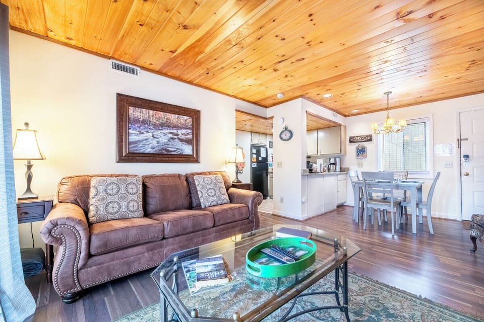 Relax in your open-concept living space featuring warm wood ceilings, leather seating, and a fully equipped kitchen perfect for your mountain getaway.