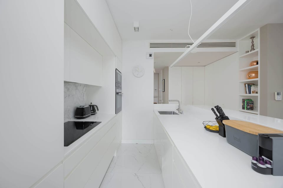A modern kitchenette area with a dark countertop contrasts beautifully with white cabinetry. The space looks both practical and elegant.