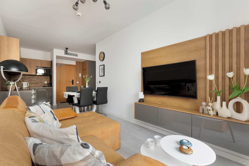 A contemporary living room with a wall-mounted TV, decorative wood paneling, and neutral-toned furniture.