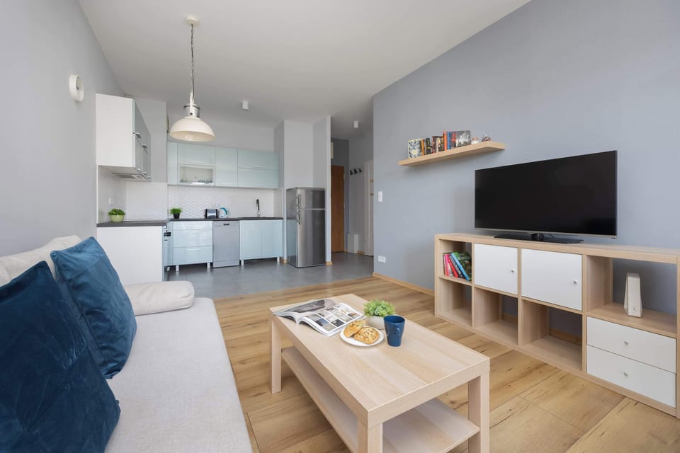 Open-plan layout connects the kitchen and living room, emphasizing a sense of flow and modern utility. White walls and light wood accents keep the aesthetic feeling fresh and organized.