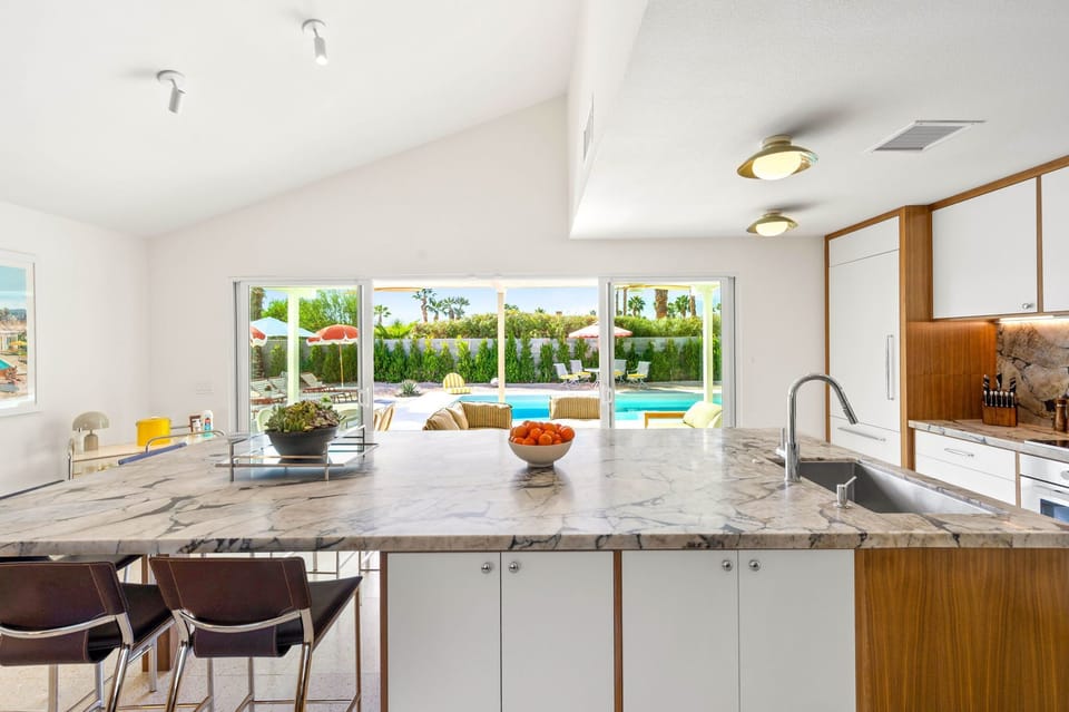 Your gourmet kitchen opens to sparkling pool views through floor-to-ceiling windows, creating the perfect entertaining space.