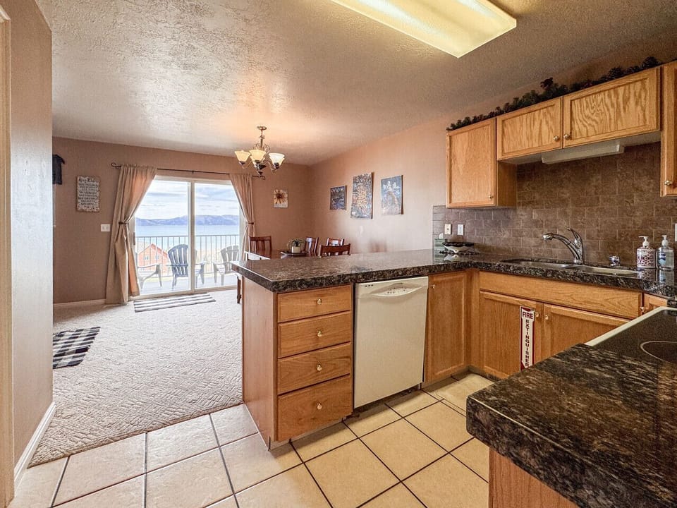 Open kitchen with granite counters flowing into dining area and balcony with scenic lake views