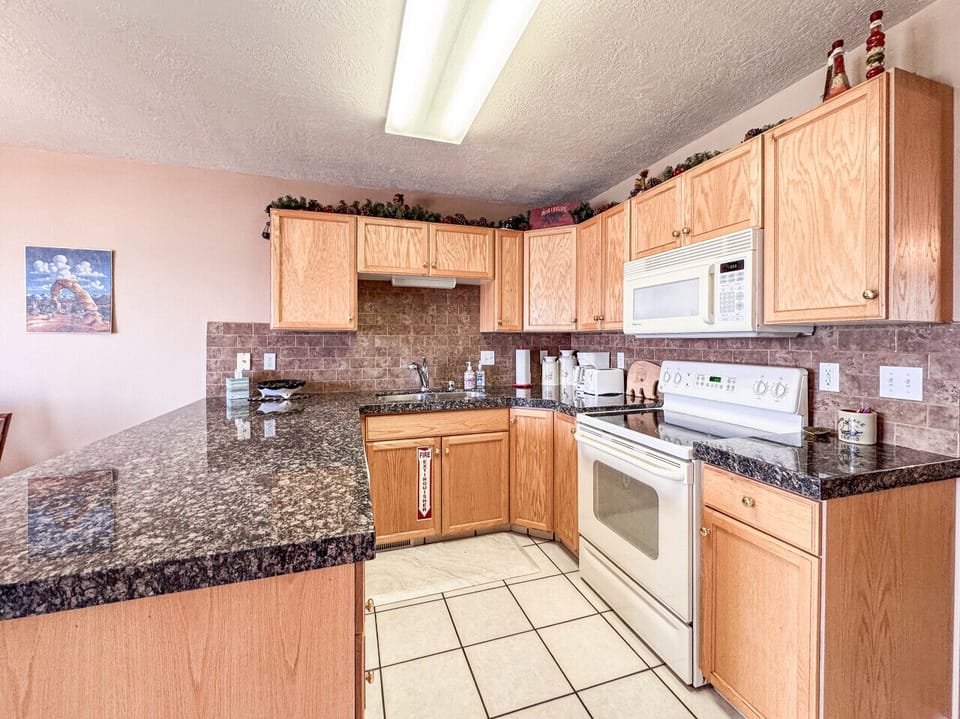 Bright kitchen with granite countertops, warm wood cabinets, and plenty of space for cooking