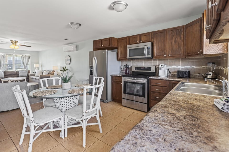 Your fully equipped kitchen flows seamlessly into the dining space, featuring granite countertops and stainless steel appliances for memorable meal preparations.