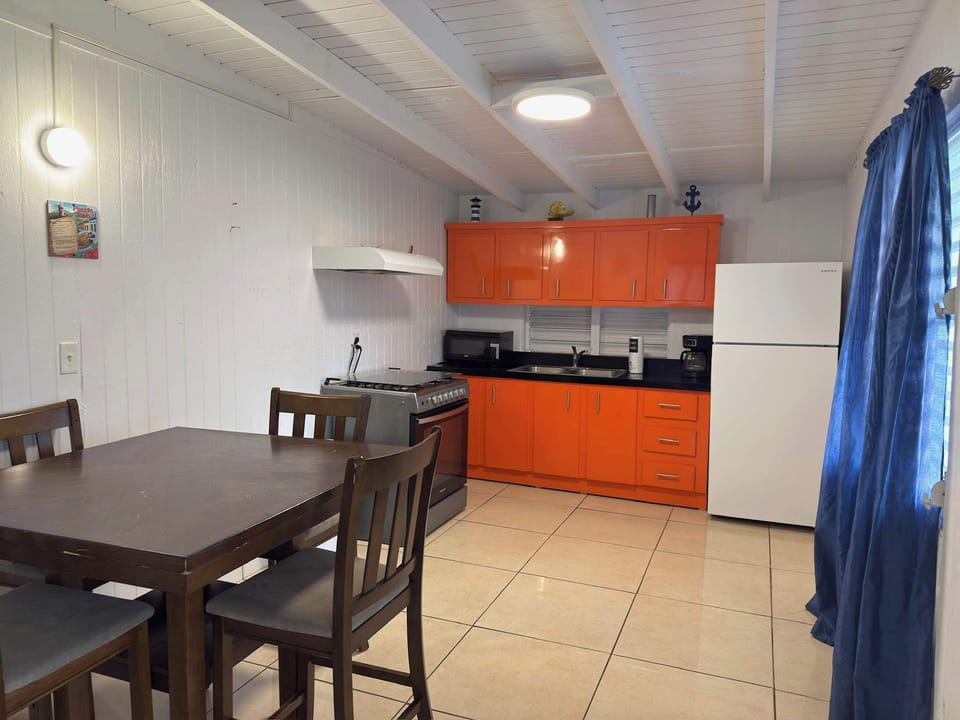 Dining area with a full kitchen, bright orange cabinetry, and everything needed for easy meals.