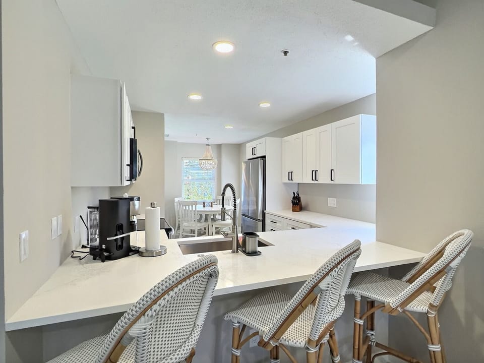 Fully equipped kitchen with an island, breakfast bar seating, stainless steel appliances, and ample counter space