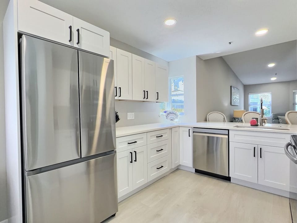 Kitchen featuring stainless steel refrigerator, white cabinetry, and modern finishes throughout
