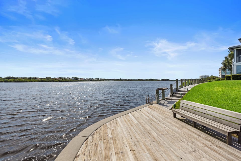 Wooden boardwalk along the waterfront with benches offering sweeping views of the bay and surrounding grounds