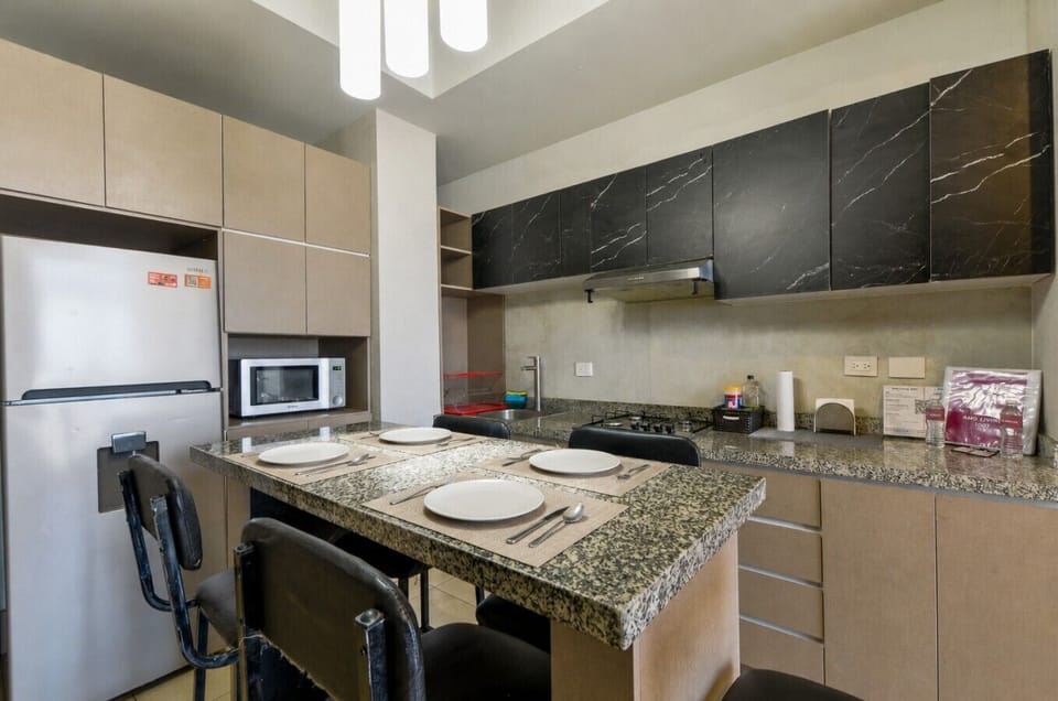 Cocina equipada con estufa, microondas, refrigerador y todos los utensilios necesarios para preparar tus comidas con facilidad.