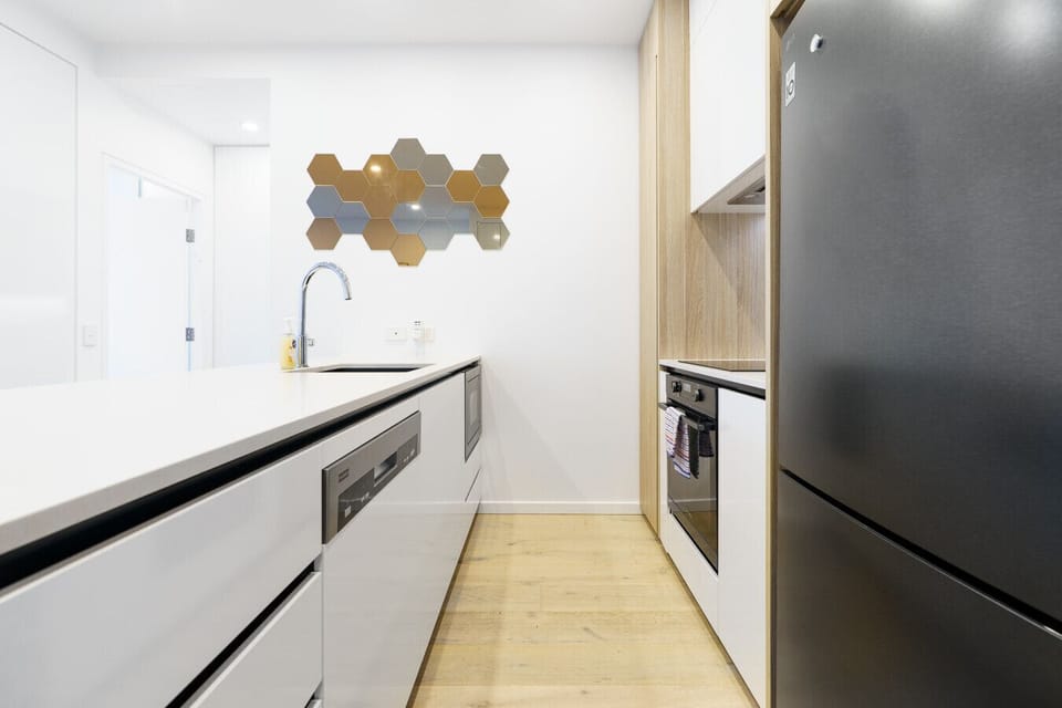 Sleek and modern kitchen featuring quality appliances and plenty of bench space for preparing meals at home.
