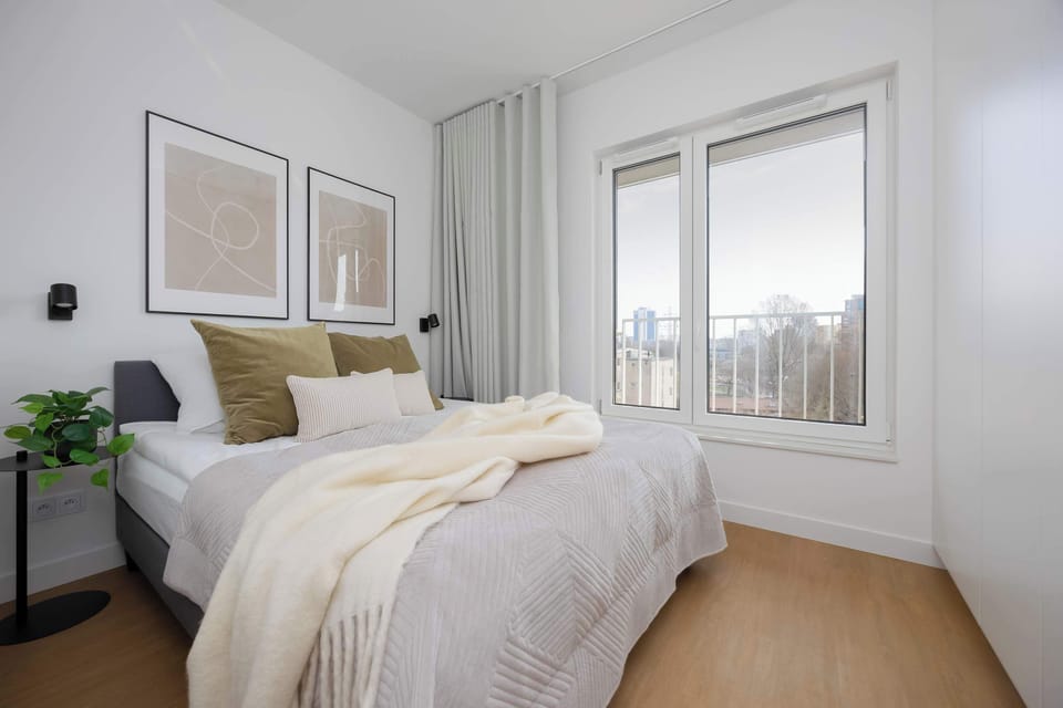 Bright bedroom with double bed, large windows and soft neutral decor