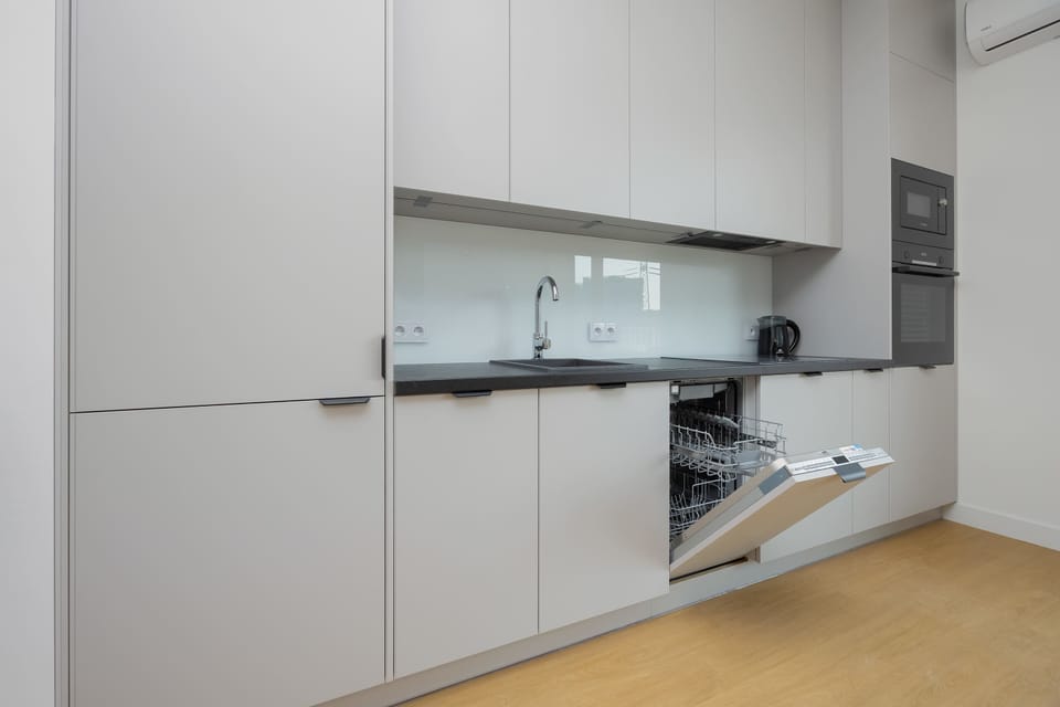 Modern kitchen with white cabinets, built-in appliances and wooden floor