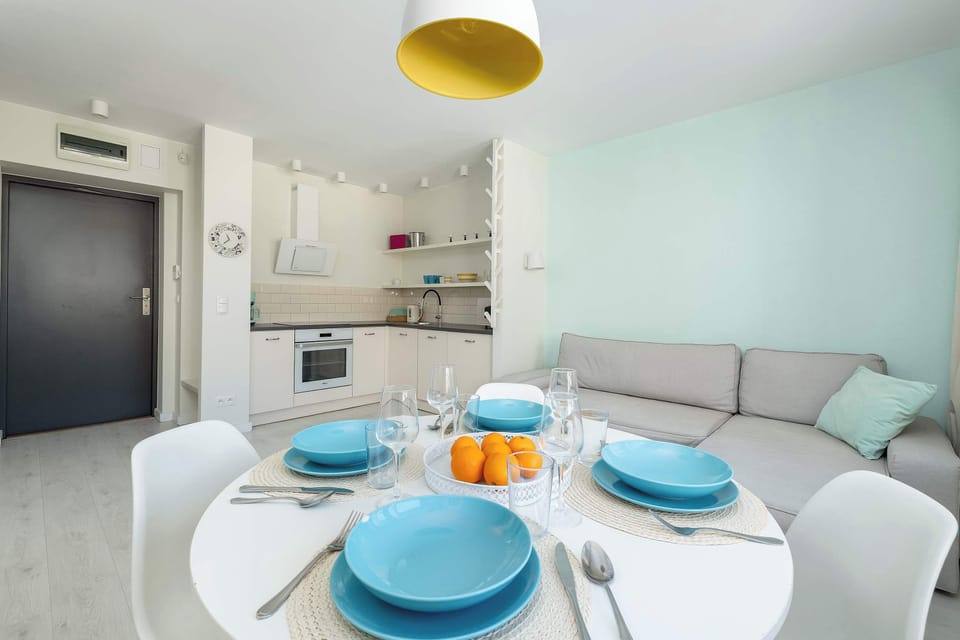 A dining nook with a round table set with plates and cups. The adjacent sofa and window make it a pleasant spot for meals and relaxation.