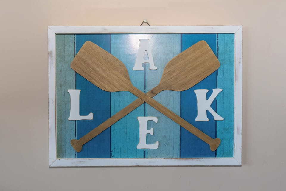 Beautiful lake-themed décor greets you with crossed wooden oars spelling LAKE in coastal blue tones, setting the perfect waterfront mood for your stay.