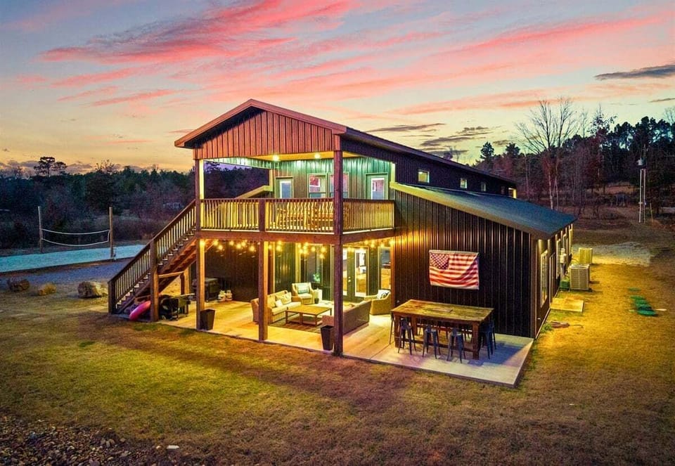 The illuminated exterior at sunset makes a striking first impression, blending modern design with rustic charm.