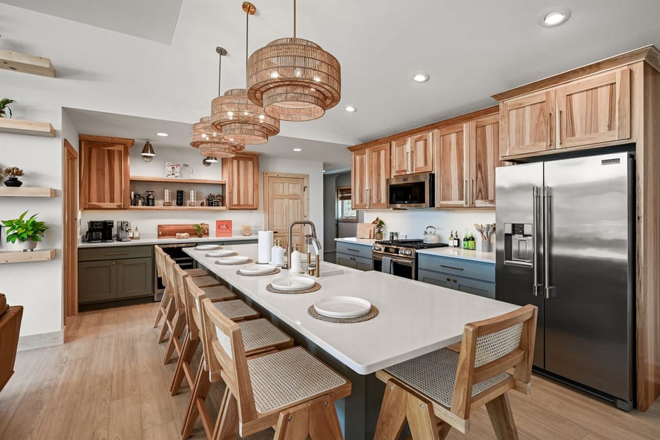Kitchen — Fully stocked kitchen to host groups up to 17. Seat 7 at the island and antoher 10 at the dining table. The kitchen opens up to the living room & dining area with expansive views outside to the upper deck and lake.