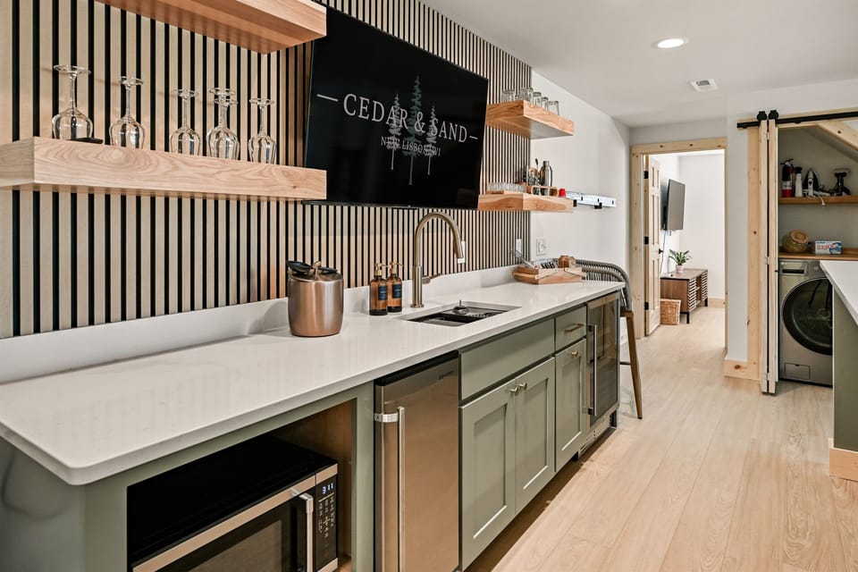 Wet bar in lower level — stock with tumbers, pint glasses, shot glasses, a shot-ski, moscow mules, an undercounter ice machine, beverage fridge, and microwave