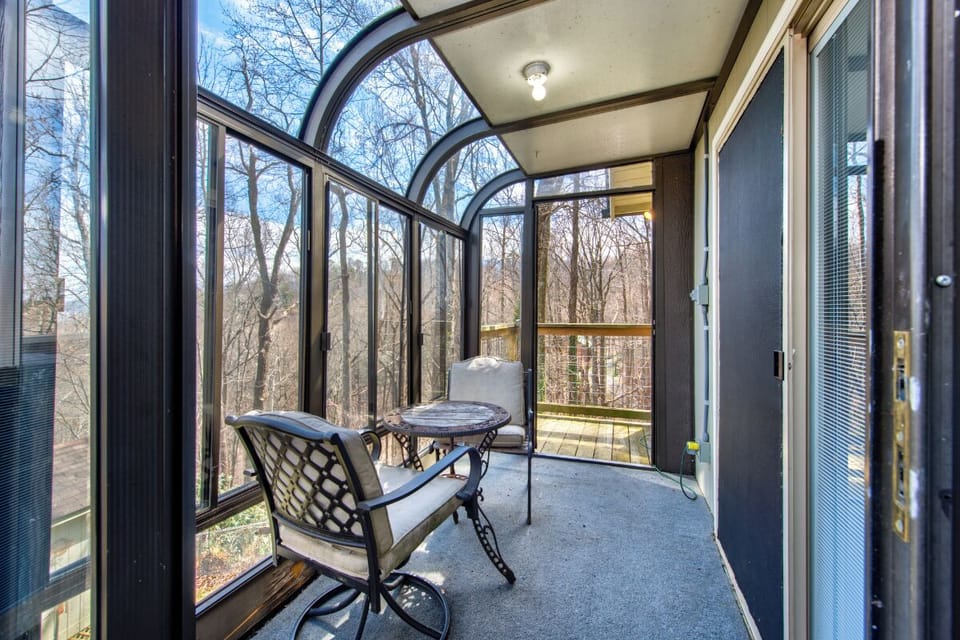 Your private glass-enclosed sunroom offers a peaceful retreat with forest views and comfortable seating for morning coffee or evening relaxation.