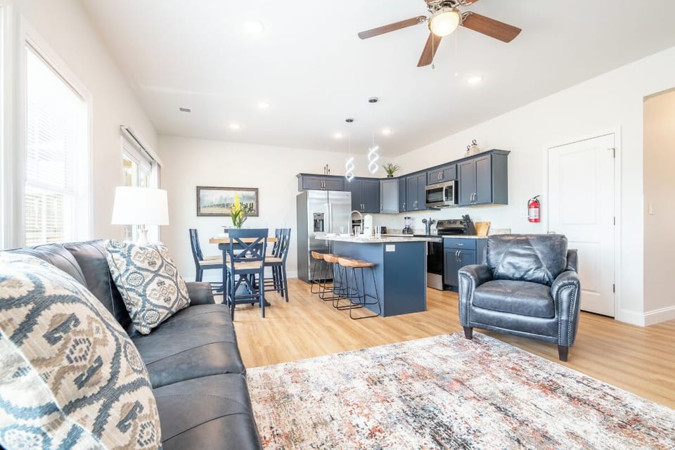 Relax in your bright open-concept space where modern navy kitchen flows seamlessly into cozy living area with plush seating.