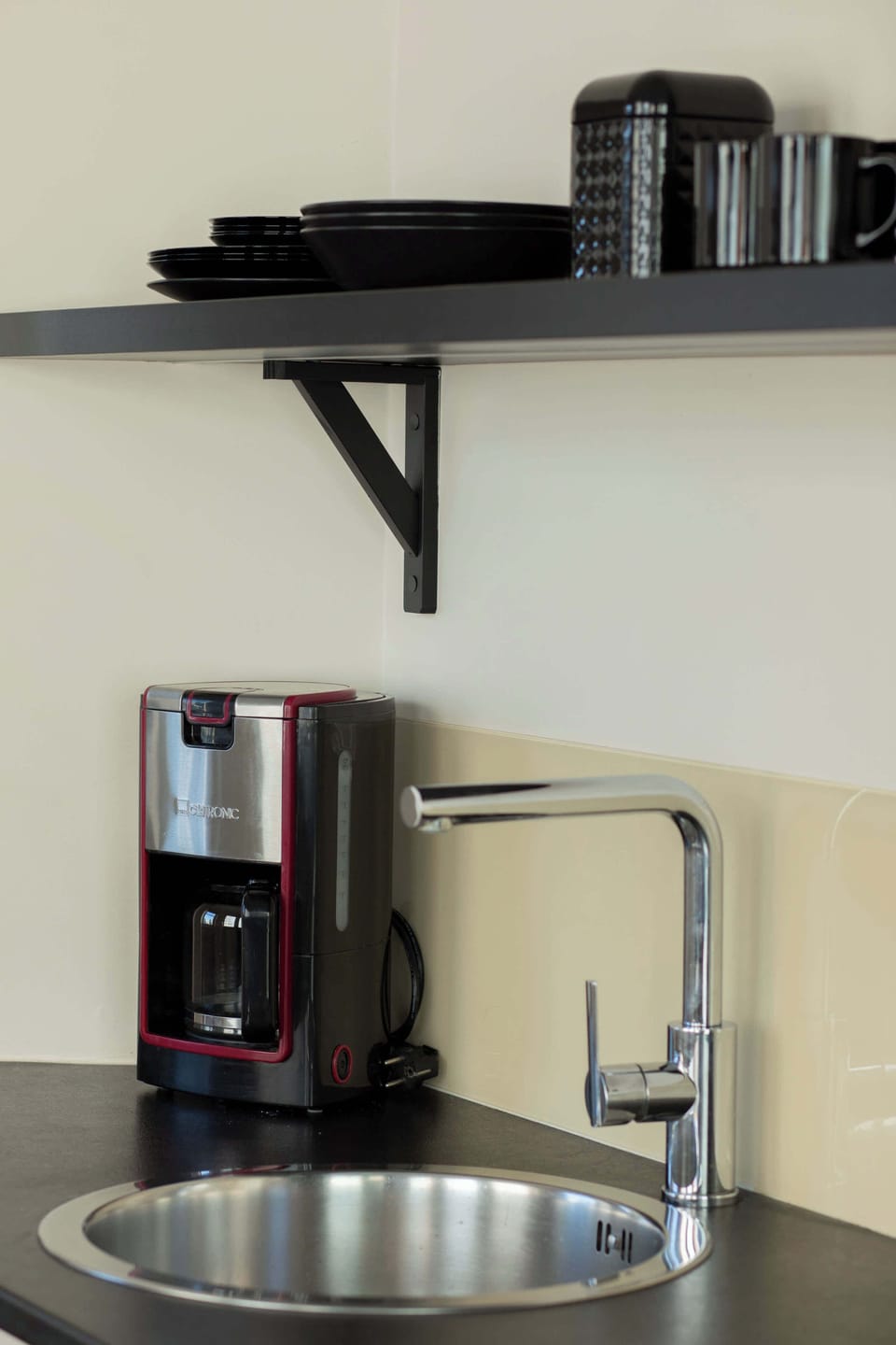 A coffee station with appliances and cups arranged neatly. The space is functional and ready for daily use.