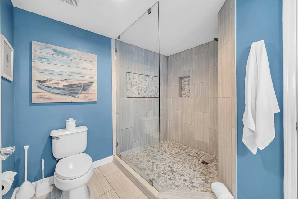 Refresh in your stylish bathroom featuring a spacious glass-enclosed shower with elegant tile work and coastal-inspired decor.