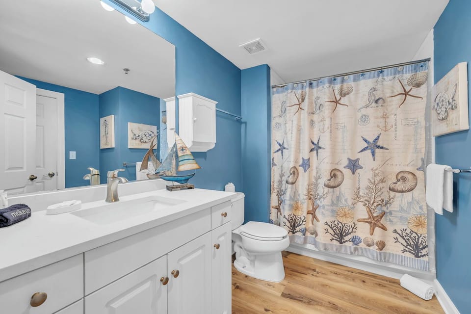 You'll love freshening up in this charming coastal-themed Guest Bathroom with its soothing blue walls, nautical decor, and spacious shower-tub combo.