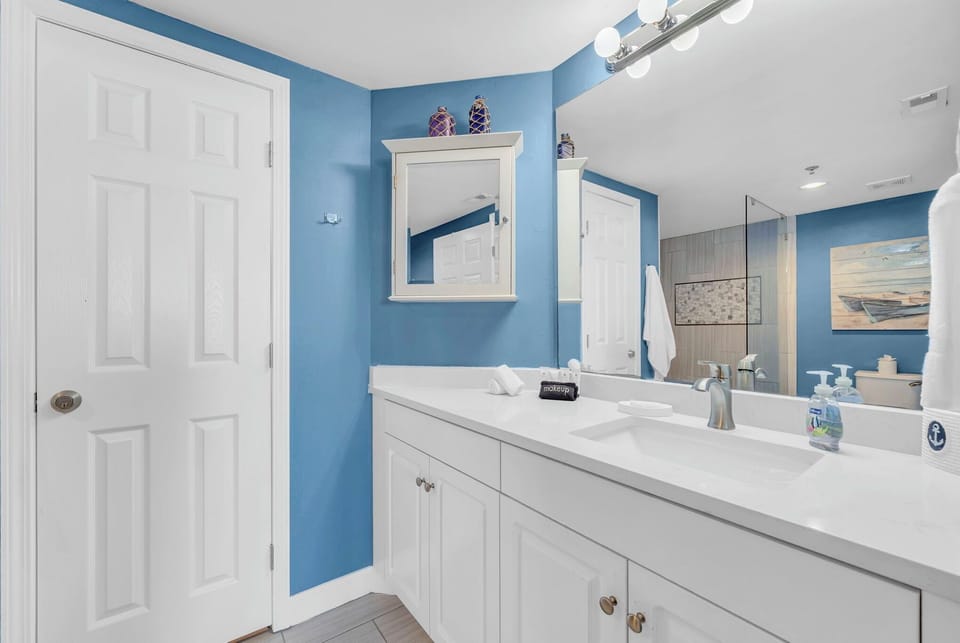 Freshen up in your bright Master Bathroom with coastal blue walls and pristine white vanity, complete with soft towels and modern amenities.