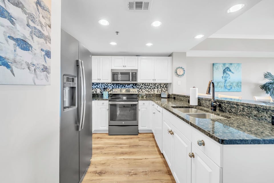 Prepare meals in a clean, airy kitchen with crisp finishes and a vibrant coastal-inspired tile backsplash.