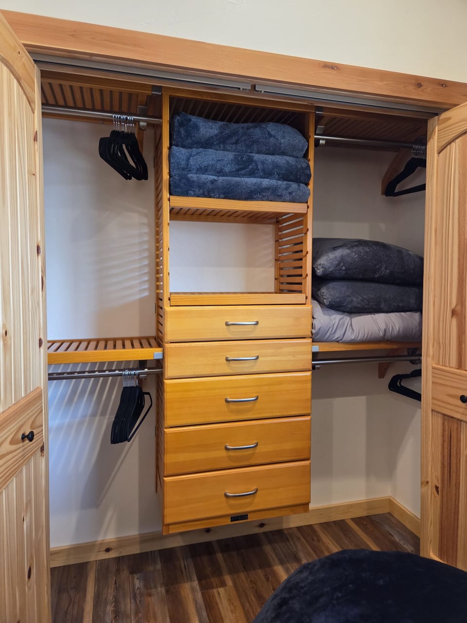Spacious wood closet with shelves, hangers, and extra linen storage