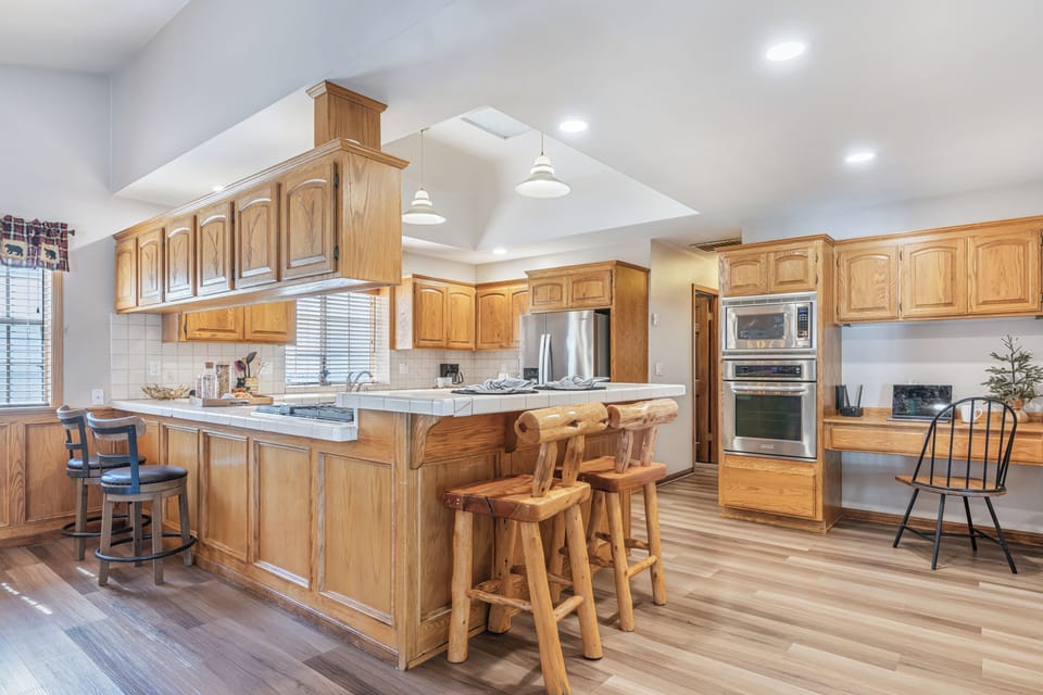 Spacious cabin-style kitchen with a large island, rustic log barstools, and stainless steel appliances—perfect for gathering and cooking together.