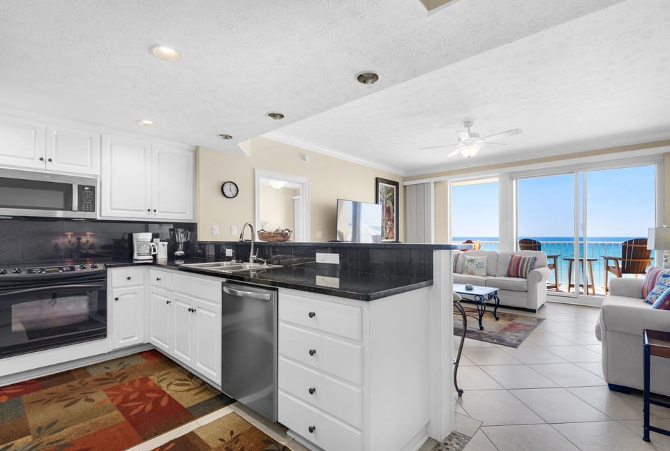 Your sleek kitchen flows into the living space where stunning ocean views await through floor-to-ceiling windows.