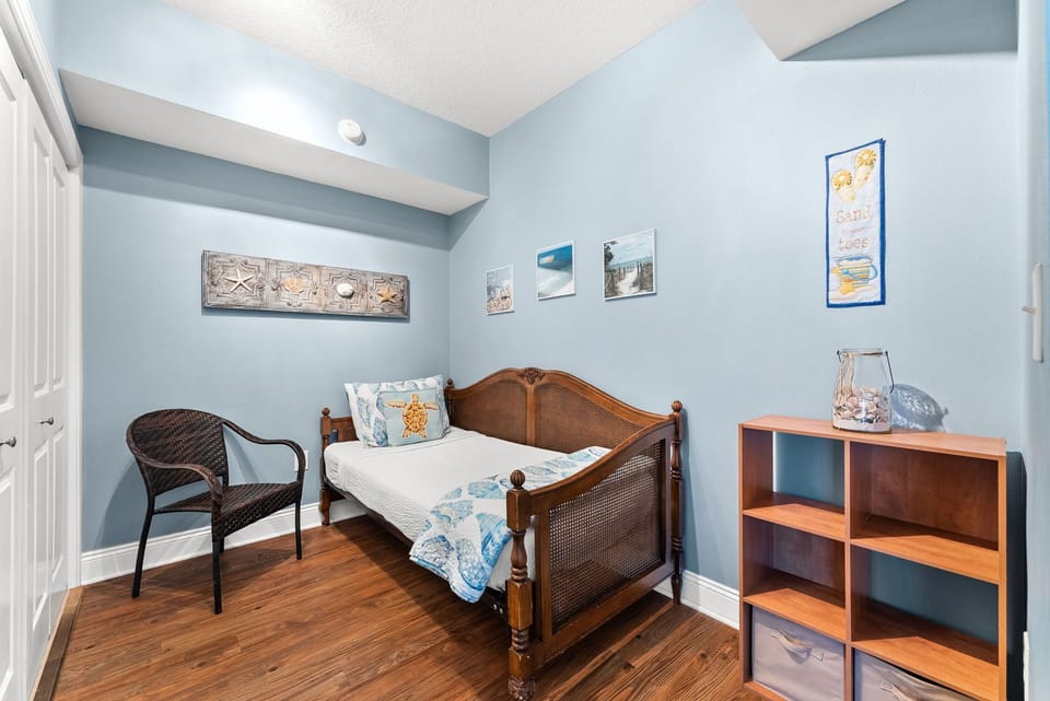 Your cozy bedroom features ocean-themed decor, warm hardwood floors, and beach artwork that create a peaceful coastal retreat.