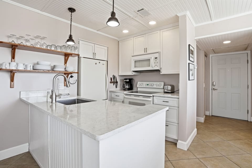 Coastal Kitchen with Easy, Functional Layout – Shipwatch 300 - This coastal kitchen features open shelving and an easy layout, making it comfortable for quick meals and gathering between beach outings.