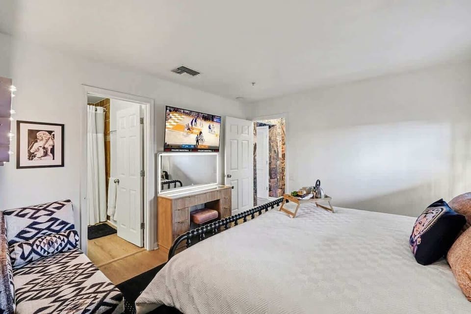 Primary Bedroom featuring a King bed, smart TV, get-ready vanity, chaise lounger chair, walk-in closet, and an en-suite bathroom.