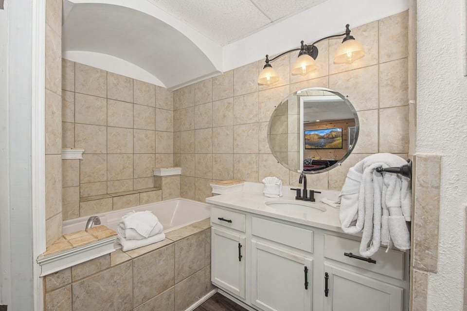 Unwind in your elegant bathroom featuring a deep soaking tub, warm lighting, and plush towels for the perfect relaxation retreat.