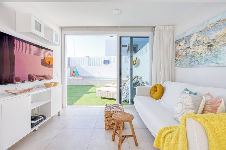 Bright living room with sofa, TV, and direct access door to the terrace with private pool, blending indoor and outdoor comfort