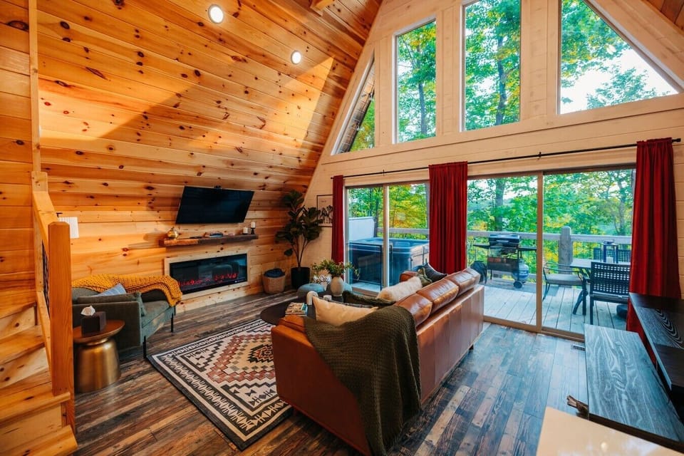 Gather in the spacious living room after hiking, with a glowing fireplace, TV, and deck views nearby