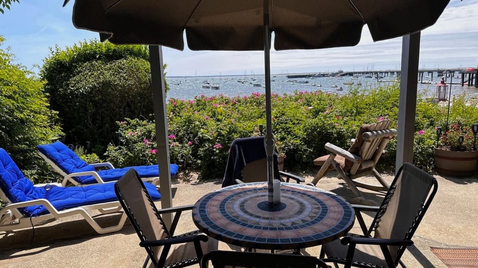 Waterfront patio with loungers, a covered table, and sweeping harbor views